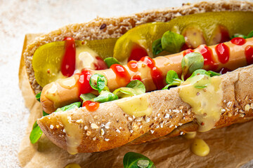Hot Dog sausage on bun, tomato sauce, pickled cucumber, greens lettuce leaf takeaway food tasty fresh eating cooking appetizer meal food snack on the table