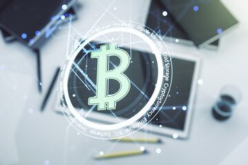 Double exposure of creative Bitcoin symbol hologram and modern digital tablet on background. Mining and blockchain concept