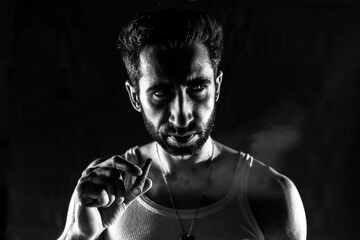 Smokey Contemplation: 30-Year-Old Man in White Tank Top, Short Beard, Narrow Black and White Portrait
