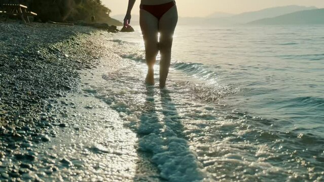 Woman walking on beach. As the sun sets; waves, a tranquil atmosphere, a perfect holiday. Holiday concept.