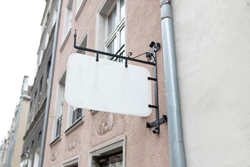 Mock up of a white blank empty vintage sign for cafe, restaurant name and logo, in an old town city. Signboard mockup