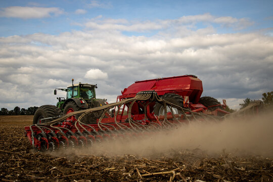 tractor with red planter in field sowing wheat