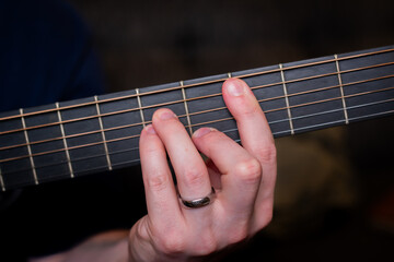 A man's hand gracefully plays a chord on the acoustic guitar, weaving a harmonious melody that...