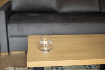 Glass of fresh water on wooden table indoors. Drinking clear water in the morning for health. Refreshing drink, Health benefits of drinking enough water concepts.