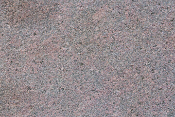 Granite texture. Natural pink granite with a grainy pattern. Stone background. Solid rough surface of rock. Durable construction and decoration material. Close-up.