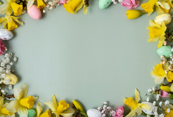 Spring flowers ans easter eggs border on green background with copy space. Easter greeting card template