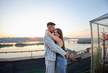 Fototapeta na wymiar A young couple kisses and embraces during a romantic rooftop date