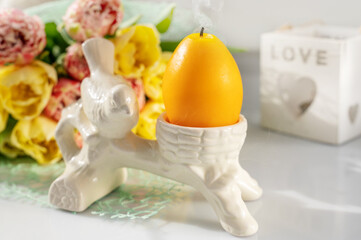 Egg-shaped candle with eggs and spring tulips on a light background. Easter composition