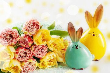 Easter bunny figures in an Easter composition. Yellow and red tulips with Easter bunnies in the foreground