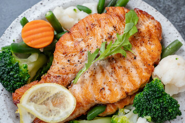 Salmon steak with vegetables cauliflower, broccoli, carrots and green beans. Salad of arugula and vegetables with salmon.