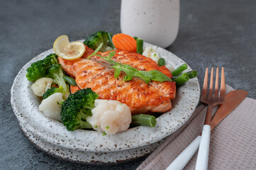 Salmon steak with vegetables cauliflower, broccoli, carrots and green beans. Salad of arugula and vegetables with salmon