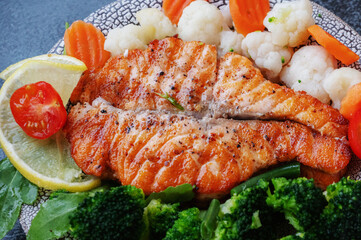 Salmon steak with vegetables cauliflower, broccoli, carrots and green beans. Salad of arugula and vegetables with salmon. Close-up