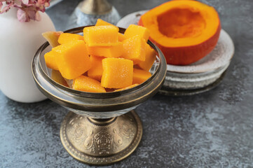 Homemade pumpkin and agar-agar gummies. Orange jelly candies served on a plate with pumpkin in the background.