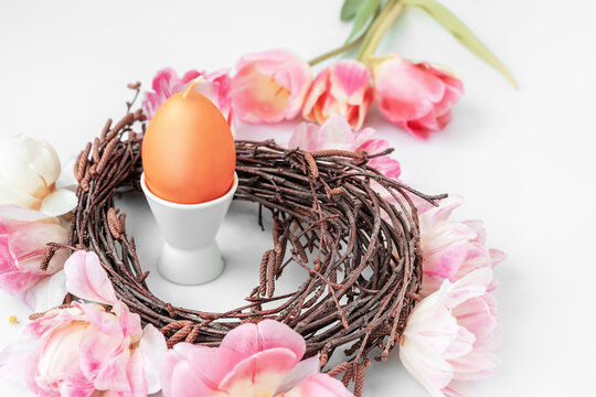 Candle in the form of an Easter egg in a nest. Easter decoration on a wooden table