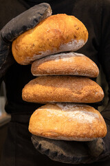 A baker holds freshly baked bread in his hands