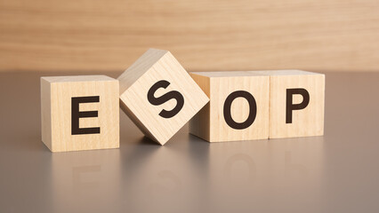 four wooden cubes with the letters ESOP on the bright surface of a brown table, business concept