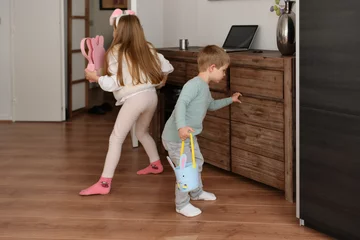 Gardinen Children at home collect chocolate eggs in a basket Easter © o1559kip