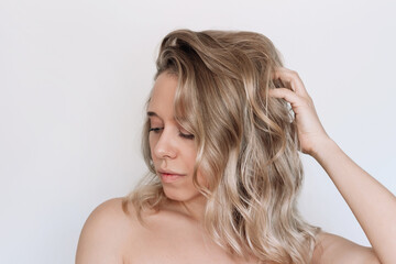 Young blonde woman with voluminous wavy hair isolated on a white background. Result of coloring,...