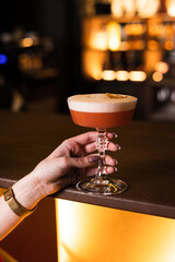 The girl's hand holds a cocktail glass at the bar