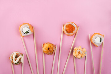 sushi and rolls on a pink background with chopsticks