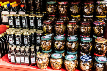 Romanian traditional food and drink, jars of pickled mushrooms, black cherries jam and bottles with alcohol.