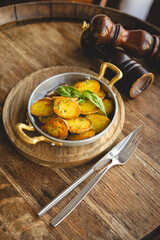 Country potatoes, fried potato slices in a frying pan on a wooden background.