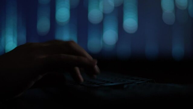 Hands of a cybercriminal working with a computer keyboard. On a blue background
