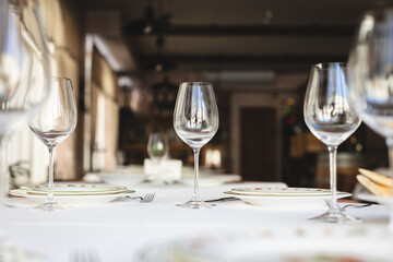 Table service. Restaurant, wine glasses, white tablecloth and dishes.