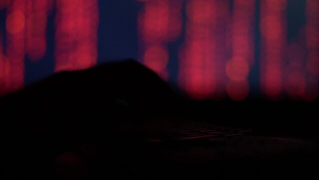 Hands of a cybercriminal working with a computer keyboard. On a red background