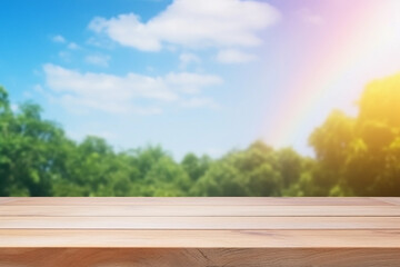 Empty wooden deck table on the green forest and blue sky with rainbow background. Backdrop for mockup and promotion design.