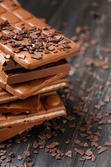 Stack of chocolate and scattered chocolate chips on wooden background