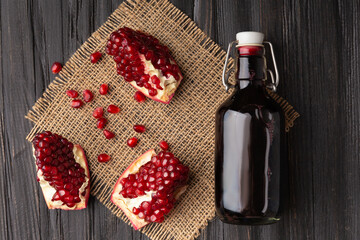 Pomegranate, scattered seeds and pomegranate juice on a wooden background .