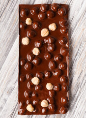 Handmade chocolate with hazelnuts on a gray wooden background, close-up.