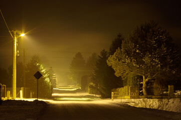 Widok nocą na ośnieżoną ulicę na wsi.
