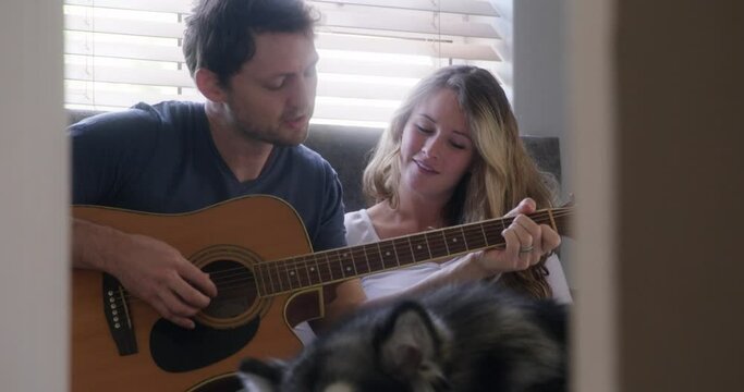 Couple, playing guitar with dog at house for love and bonding, happy in bed with pet. People with domestic animal, husky and musical instrument, time together with trust, commitment and creativity