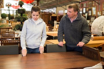 Modern family couple selecting furniture for apartment in furnishing salon ..