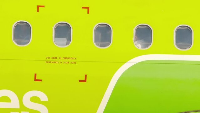 Green passenger plane. The aircplane fuselage and portholes close-up.