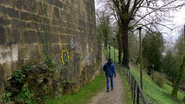 Latino man walks towards camera on Angouleme ramparts