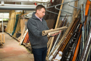 Portrait of young woman buying bamboo poles in gardening shop