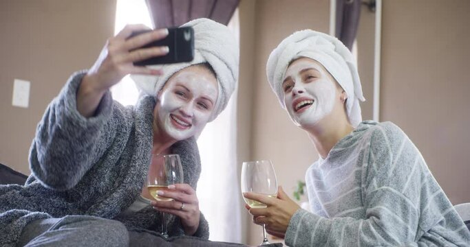 Selfie, friends and mask for skincare or beauty, social media post and update on mobile application. Women, bonding and alcohol for relaxing and funny face for picture, humor and comedy at spa