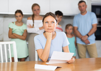 Frustrated woman sits in kitchen and reads unpleasant news in letter. Rent increase, penalty for...