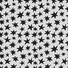 Freehand drawn black stars on gray background seamless pattern