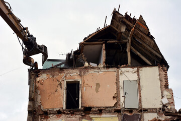 Dismantling a building on a city street with an excavator. Reconstruction and renovation of cities