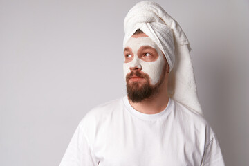 Man in white tshirt apply facial mask stand against white background. Beauty treatment, grooming...