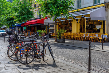 Fototapeta premium Typical view of the Parisian street with tables with tables of cafe in Paris, France. Architecture and landmark of Paris. Cozy Paris cityscape