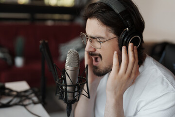 A male vocalist passionately performs into a studio microphone, captured mid-song during a...