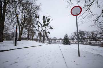 Znak zakazu ustawiony w kierunku ścieżki prowadzącej nad wodę wieczorem w pochmurny zimowy...