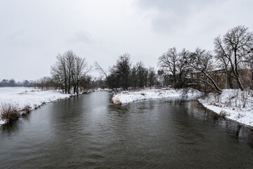Zimowa panorama rzeki Osobłogi w popołudniowych godzinach pochmurnego szarego dnia w Zachodniej Polsce - obrazy, fototapety, plakaty