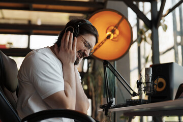 A sound producer with headphones laughs while enjoying a light-hearted moment during a studio...