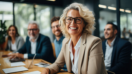 Group of adults led by a smiling mature business woman in her 50s in a conference room - Powered by Adobe